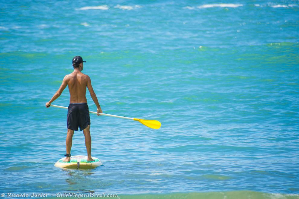 Imagem de um homem praticando standup paddle no mar da Praia do Félix.
